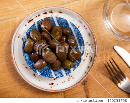 On white plate lies portion of large ripe green olives with stone. 120235768