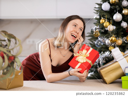 Attractive woman is preparing presents and discussing it with someone on a mobile phone Attractive woman is preparing presents and discussing it with someone on a mobile phone 120235862