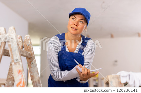 Woman foreman checks the completed construction work on drawing Woman foreman checks the completed construction work on drawing 120236141