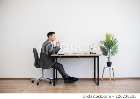 Asian businessman working on laptop in minimalist office setting Asian businessman working on laptop in minimalist office setting 120236183