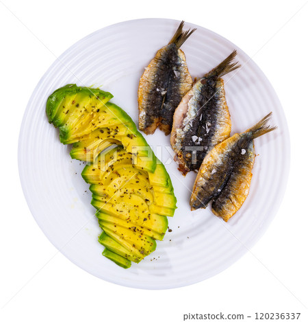Smoked fillet of sardine carcass is served in plate with slices of ripe avocado. 120236337