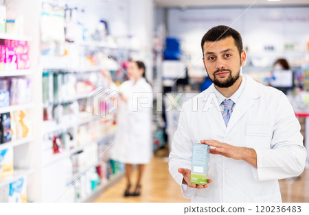 Portrait of man druggist in drugstore with drug package 120236483
