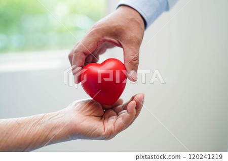 Asian elder senior woman patient holding red heart in hospital. 120241219
