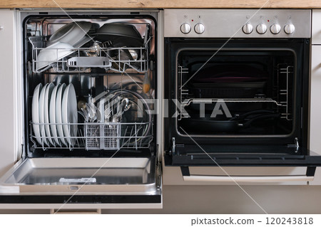Open dishwasher placed beside an oven. Dishwasher loaded with clean dishes. Empty oven Open dishwasher placed beside an oven. Dishwasher loaded with clean dishes. Empty oven 120243818