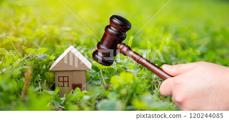 Judge's gavel near miniature wooden house outdoors. Real estate court decisions. Property inheritance litigation. Establishment of ownership. 120244085