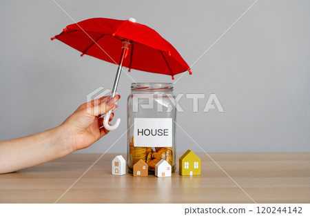 Bank of coins with word House and umbrella. Financial security and property or housing insurance concept. Investment protection and risks. Mortgage, loan. Wooden houses 120244142