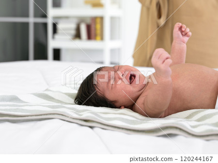 Newborn baby girl or boy crying on white bed at home 120244167