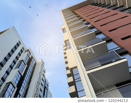 View of multi-storey buildings in a modern residential complex on a sunny day a blue sky background. Skyscrapers and real estate View of multi-storey buildings in a modern residential complex on a sunny day a blue sky background. Skyscrapers and real estate 120244213