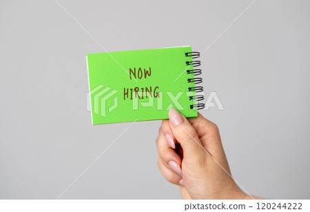 Notebook with the inscription Now hiring in a hand. Employee Search. Attraction to work. Human Resource Management. Hire. Promotion. Working staff. Business concept 120244222
