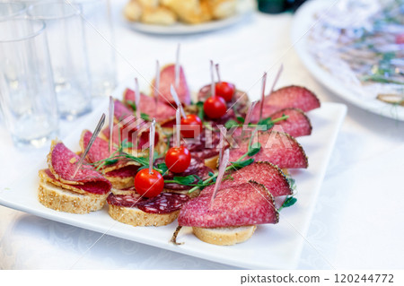 Canape with Italian salami, french baguette and ripe cherry tomatoes 120244772