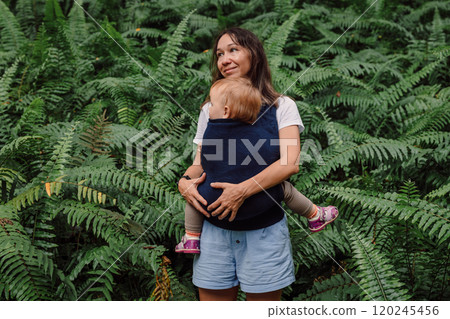 Portrait of mother with her cute baby daughter in park between fern leaves Portrait of mother with her cute baby daughter in park between fern leaves 120245456