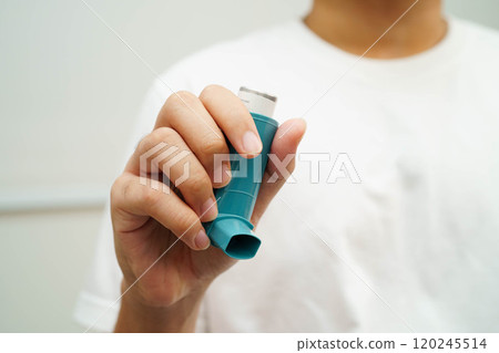 Asthma and chronic obstructive pulmonary disease COPD, Asian young man using metered dose inhaler MDI. Asthma and chronic obstructive pulmonary disease COPD, Asian young man using metered dose inhaler MDI. 120245514