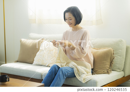 Middle-aged woman knitting in the living room Middle-aged woman knitting in the living room 120246535