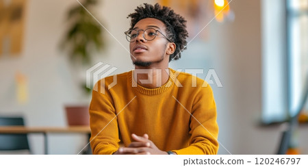 A thoughtful young man wearing glasses sits in a cozy space. He is wearing a warm sweater and seems lost in thought. This image captures a moment of reflection. AI A thoughtful young man wearing glasses sits in a cozy space. He is wearing a warm sweater and seems lost in thought. This image captures a moment of reflection. AI 120246797