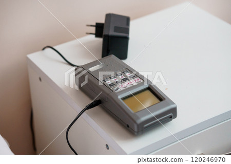 Analog Multimeter and Charger on a White Nightstand 120246970
