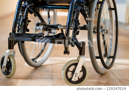 Wheelchair in a Well-Lit Corridor with Focus on Wheels and Frame 120247014