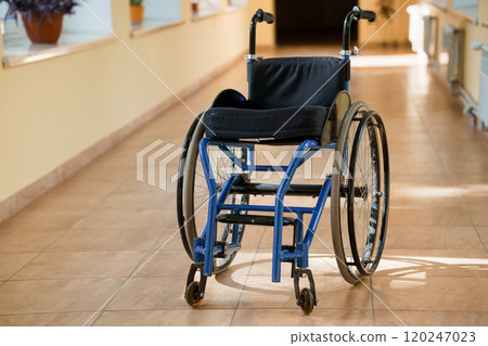 A Solitary Blue Wheelchair in a Brightly Lit Hallway A Solitary Blue Wheelchair in a Brightly Lit Hallway 120247023