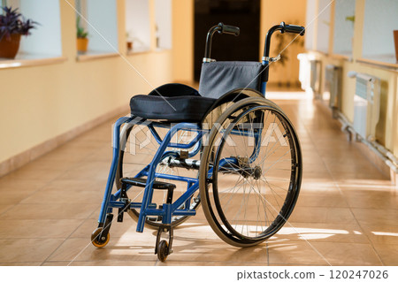 Empty Wheelchair in a Hospital Corridor with Natural Light Streaming In 120247026