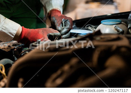 Hands Working on Car Engine with Tools and Mechanical Components 120247117