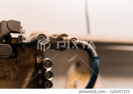 Detailed Close-Up of a Pneumatic Hose Connector Mounted in a Workshop 120247155