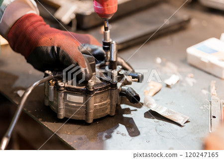 Mechanical Technician Assembling a Fuel Pump Component in a Workshop 120247165