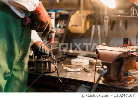 Craftsmanship in Action: A Skilled Technician Reviving Machinery in a Workshop Craftsmanship in Action: A Skilled Technician Reviving Machinery in a Workshop 120247167