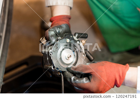 Close-Up of Technician Holding a Mechanical Component in a Workshop Close-Up of Technician Holding a Mechanical Component in a Workshop 120247191