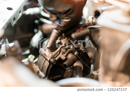 Close-Up of an Automotive Mechanic Working on a Car Engine's Water Pump Close-Up of an Automotive Mechanic Working on a Car Engine's Water Pump 120247237