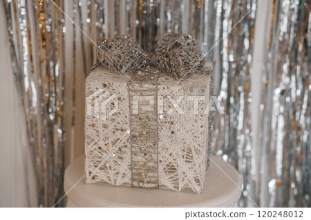 Elegant Silver and Gold Decorative Gift Box on a Stand Against Shiny Background Elegant Silver and Gold Decorative Gift Box on a Stand Against Shiny Background 120248012