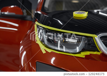 Closeup view on car headlights with attached masking tape 120248173