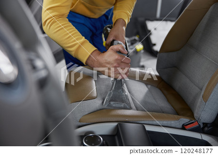 Man worker cleaning car interior with washing vacuum cleaner Man worker cleaning car interior with washing vacuum cleaner 120248177