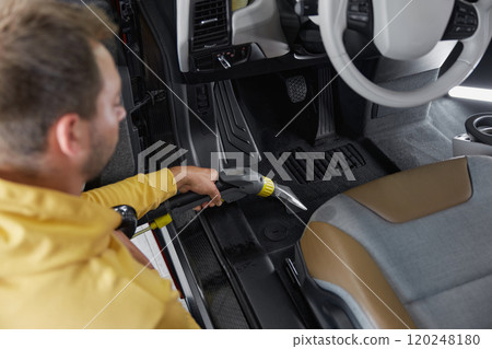 Car wash service worker vacuuming dust form back passenger seats Car wash service worker vacuuming dust form back passenger seats 120248180
