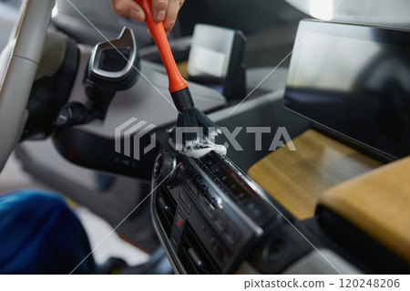Closeup male worker cleaning car interior with duster brush and detergent foam 120248206