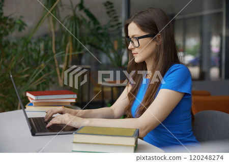 Young woman student studying via laptop computer in library 120248274