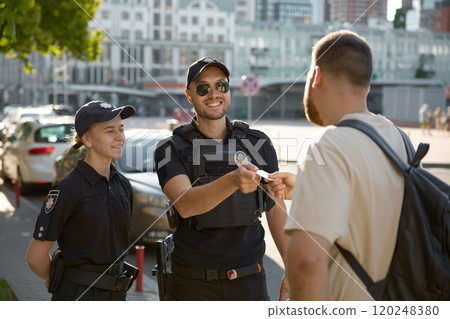 Friendly smiling patrol policeman giving back passport to citizen 120248380
