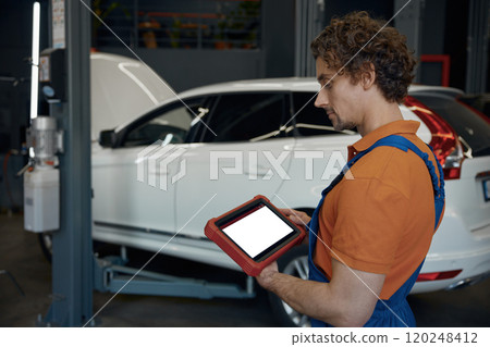 Portrait of male car technician looking at computer 120248412