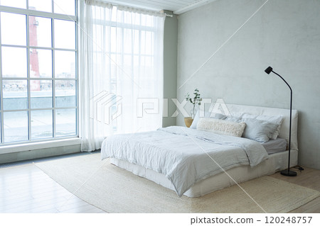 Stylish loft bedroom interior. Spacious design apartment with light walls large windows big bed. Clean modern decoration with elegant furniture in minimalist Scandinavian style 120248757