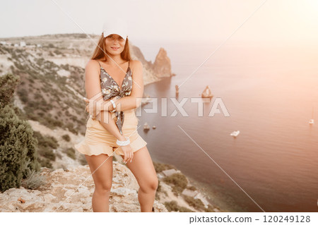 Woman travel sea. Happy tourist taking picture outdoors for memories. Woman traveler looks at the edge of the cliff on the sea bay of mountains, sharing travel adventure journey 120249128