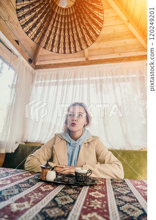 Woman in Beige Coat Sipping Coffee in a Cozy Cafe Woman in Beige Coat Sipping Coffee in a Cozy Cafe 120249201