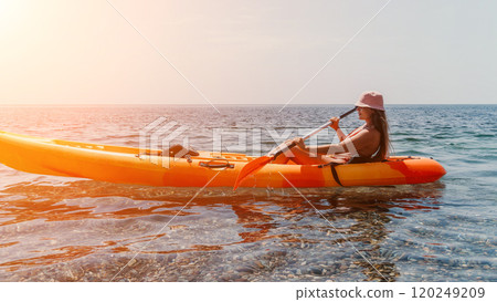 Kayaking, Woman, Sunset - A woman paddles a kayak in the ocean at sunset. Kayaking, Woman, Sunset - A woman paddles a kayak in the ocean at sunset. 120249209