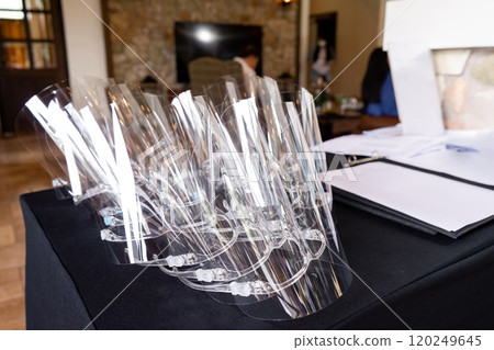 Several face shields were stacked on top of the black table, allocated to protect the staff from germs Several face shields were stacked on top of the black table, allocated to protect the staff from germs 120249645