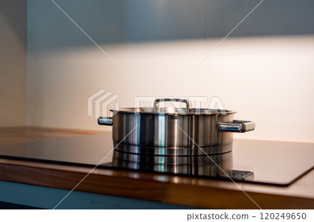 stainless steel pot on electronic modern flat stove in low light on counter kitchen room 120249650