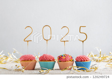 Holiday cupcakes frosted with pink buttercream frosting with gold 2025 numbers. Christmas greeting card with muffins. Holiday cupcakes frosted with pink buttercream frosting with gold 2025 numbers. Christmas greeting card with muffins. 120249724
