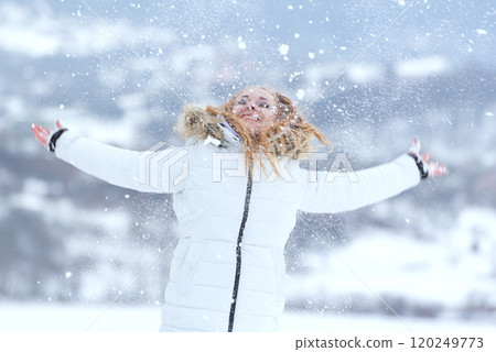 Red-haired girl in white clothes rejoices in the snowfall smiling and laughing. Winter time. Red-haired girl in white clothes rejoices in the snowfall smiling and laughing. Winter time. 120249773