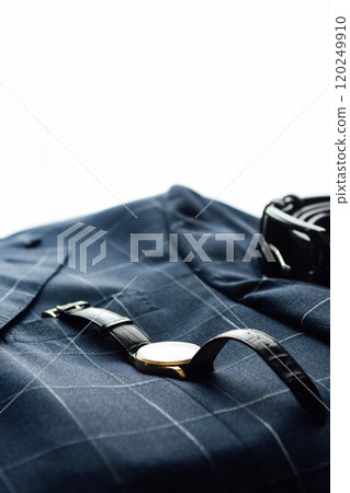 Groom's wedding details. Watch, rings and belt placed on a checkered jacket 120249910