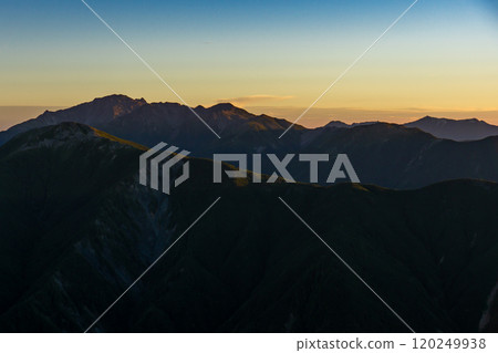 Magic hour view of the Shirane Sanzan mountains from the summit of Mt. Senmai. Climbing Mt. Akuzawa and Mt. Arakawa in the Southern Alps. Magic hour view of the Shirane Sanzan mountains from the summit of Mt. Senmai. Climbing Mt. Akuzawa and Mt. Arakawa in the Southern Alps. 120249938