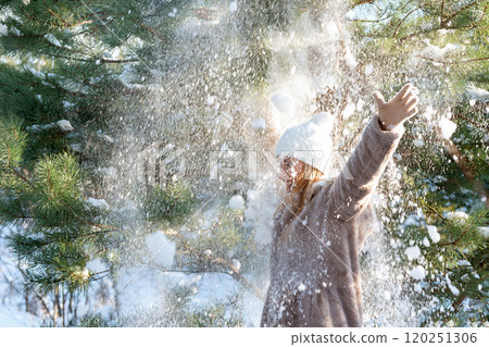 Young woman throwing snow in the air. Snowfall in winter forest. 120251306