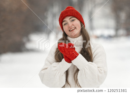Portrait of a beautiful girl in a white sweater and red hat in winter Portrait of a beautiful girl in a white sweater and red hat in winter 120251381