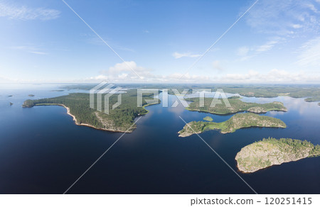 Aerial top view to island Kilpola overgrown with sparse trees in summer sunny day. Skerries Ladoga lake consisting of 650 rocky islands and steep cliffs. National park, Karelia, Russian nature. Aerial top view to island Kilpola overgrown with sparse trees in summer sunny day. Skerries Ladoga lake consisting of 650 rocky islands and steep cliffs. National park, Karelia, Russian nature. 120251415