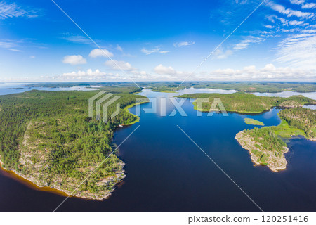 Aerial top view to island Kilpola overgrown with sparse trees in summer sunny day. Skerries Ladoga lake consisting of 650 rocky islands and steep cliffs. National park, Karelia, Russian nature. Aerial top view to island Kilpola overgrown with sparse trees in summer sunny day. Skerries Ladoga lake consisting of 650 rocky islands and steep cliffs. National park, Karelia, Russian nature. 120251416